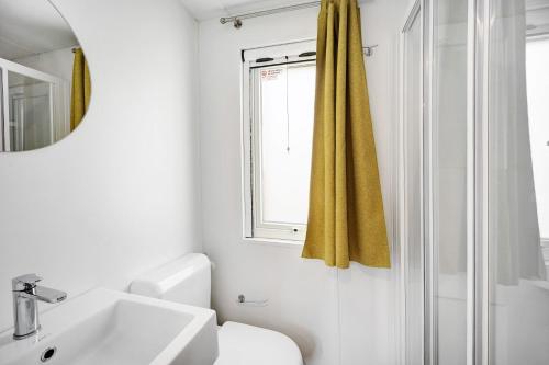 a white bathroom with a sink and a window at Mobile Home Alloro 165 in Pietra Ligure