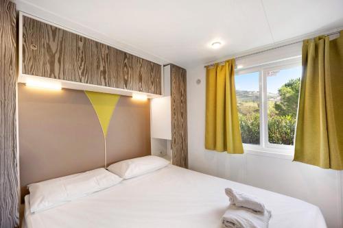 a small bedroom with a bed and a window at Mobile Home Alloro 165 in Pietra Ligure