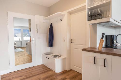 a kitchen with white cabinets and a mirror at Strandburg in Westerland