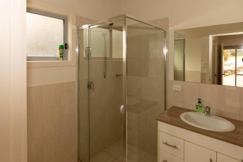a bathroom with a glass shower and a sink at River Vista at Aruma in Walker Flat