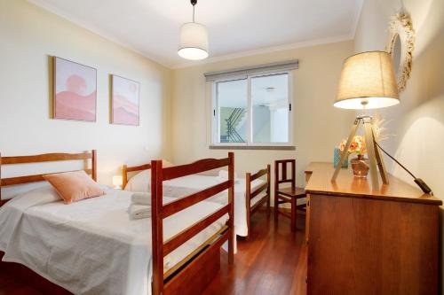 a bedroom with a bed and a desk with a lamp at Apartamento Fénix Garajau in Caniço