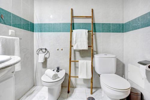 a white bathroom with a toilet and a sink at Apartamento Fénix Garajau in Caniço