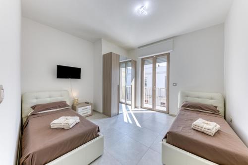two beds in a white room with a tv at Messapica Rooms in Ugento