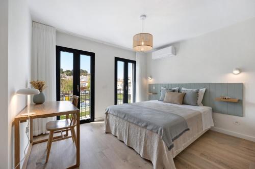 a bedroom with a bed and a desk and windows at Casa Helena in Ferragudo
