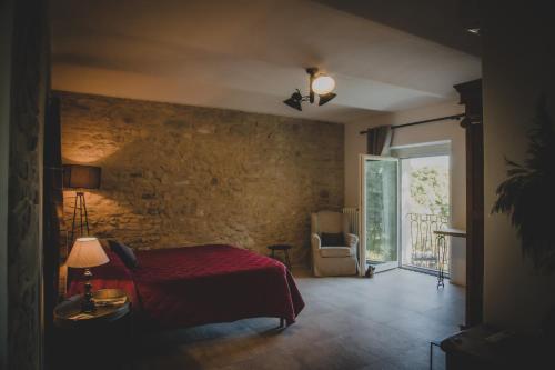 a bedroom with a red bed and a stone wall at Cascina Voglietti - Private Pool in Murisengo