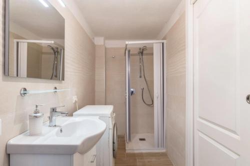 a white bathroom with a sink and a shower at Appartamento Edik in Folgaria