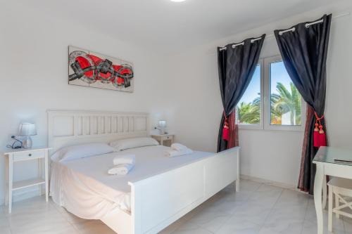a white bedroom with a white bed and a window at Villa Rosa in Benissa
