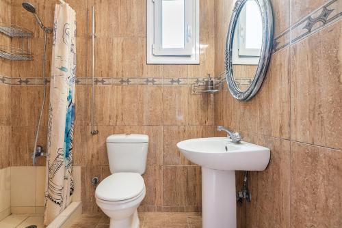 a bathroom with a toilet and a sink and a mirror at Rafaela's House in Koskinou