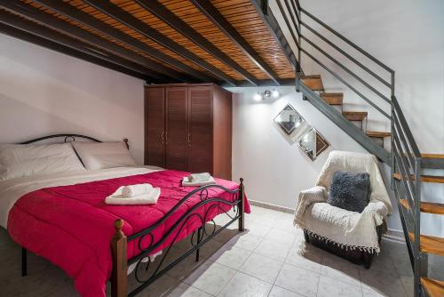 a bedroom with a bed with a red blanket and a chair at Rafaela's House in Koskinou