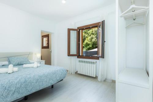 a white bedroom with a bed and a window at Sestel in Capdepera