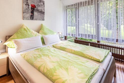 a bedroom with a bed with green sheets and a window at Ferienwohnung Fetscher 1 in Reichenau