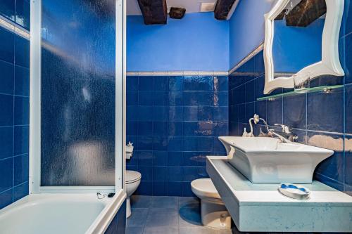 a blue bathroom with a sink and a tub and a toilet at Lago Gabriel - Villar de Posada in Caldevilla de Rengos