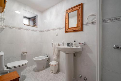 a white bathroom with a toilet and a sink at Lorences D in Caunedo