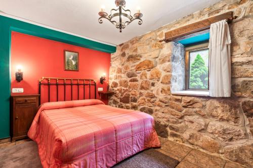 a bedroom with red walls and a stone wall at Lorences D in Caunedo