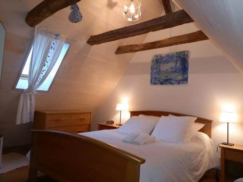 a bedroom with a white bed with two windows at Maison Typique Au Calme in Coubisou
