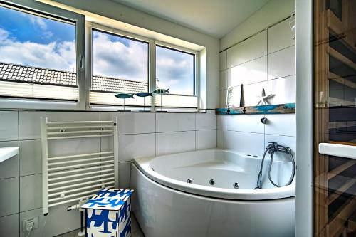 a white bathroom with a tub and a window at Boje by Seeblick ferien oro in Kappeln