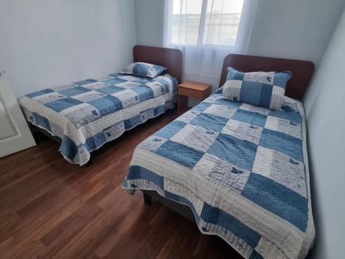 a bedroom with two beds and a wooden floor at Casa campo Quillota in Quillota