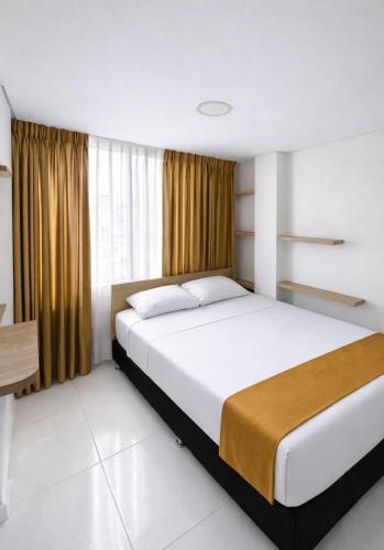 ein Schlafzimmer mit einem großen weißen Bett vor einem Fenster in der Unterkunft Hotel Adel in Manizales