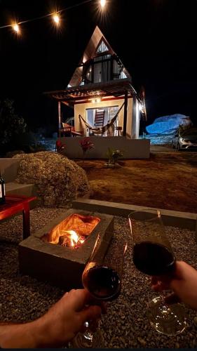 a fire pit with two people holding glasses of wine at Chale Gameleiras in Monte das Gameleiras