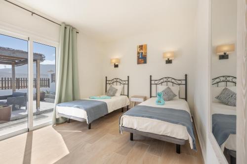 a bedroom with two beds and a balcony at Rincón del olivar in Fuerteventura