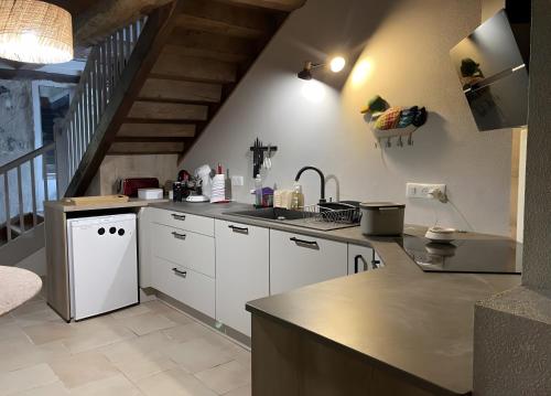 a kitchen with white cabinets and a staircase at Gîte Rosa Bonheur in Saint-Cernin