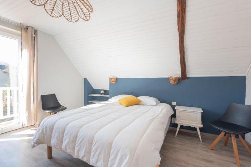 a bedroom with a bed with a blue wall and two chairs at Gite du Pibeste - 8 pers in Ouzous