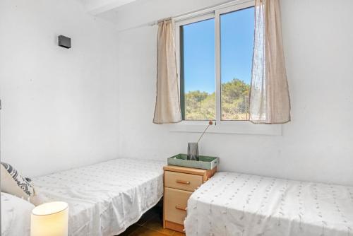 a bedroom with two beds and a window at Sa Calma House in Cala en Bosc