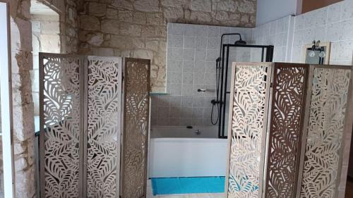 a bathroom with two wooden doors and a bath tub at Chambre Hirondelle in L'Ile-Bouchard