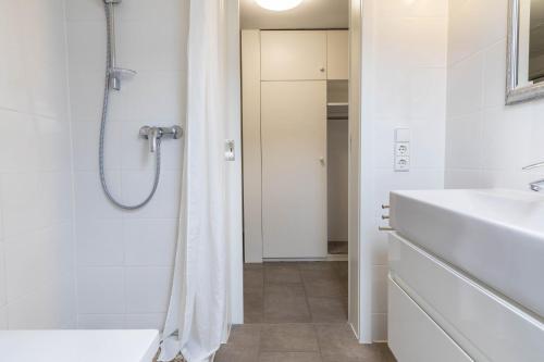 a white bathroom with a shower and a sink at Ferienwohnung Lumafe in Überlingen