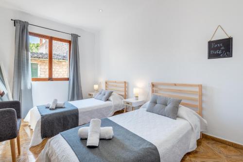 a bedroom with two beds and a chair and a window at Es Llimoner in Sóller