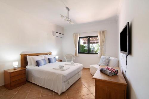 a bedroom with a bed and a tv and a couch at Villa Formosa in Almancil