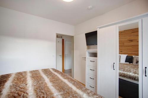 a white bedroom with a bed and a closet at Ferienwohnung Marinas Alpenblick in Inzell