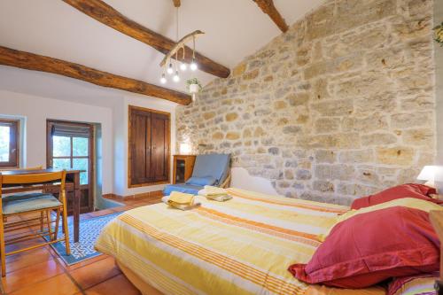 a bedroom with a stone wall with a bed and a table at Chambre La Louve in Banne