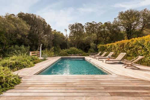 a swimming pool with chairs and a wooden deck at Casa di Pruno in Figari