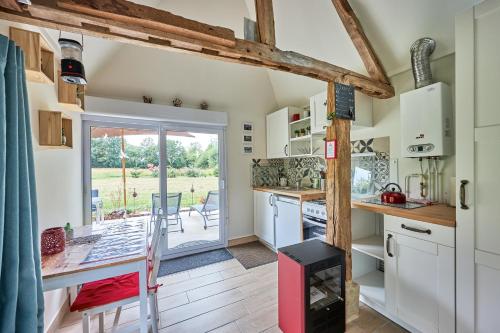 a kitchen with white cabinets and a door leading to a patio at Le chouette insolite in Cresseveuille