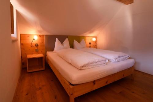 a bed with white sheets and pillows in a room at Rosengartnerhof Apt Gantkofel in Terlano