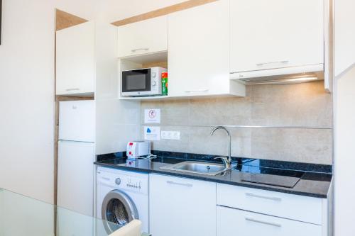 a kitchen with a sink and a washing machine at Trevol Suits in Cielo de Bonaire 
