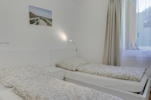 two beds in a white room with a window at Apartment Habicht in Mühlbachl