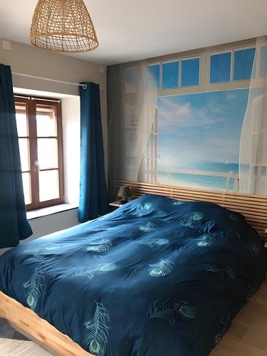 a bedroom with a blue bed with a painting of the ocean at Gîte Les Aubennes in Fromelennes