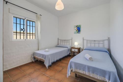 two beds in a room with a window at Villa Ibicenca in Vejer de la Frontera