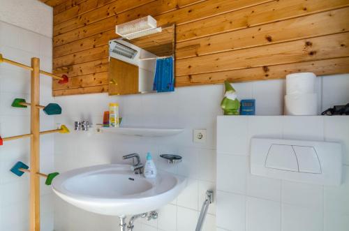 a bathroom with a white sink and wooden walls at Rose Garden in Heiligenberg