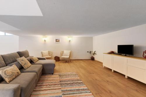 a living room with a couch and a flat screen tv at Caparica Sun Beach Villa in Charneca