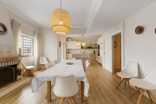 a white dining room with a table and chairs at Caparica Sun Beach Villa in Charneca
