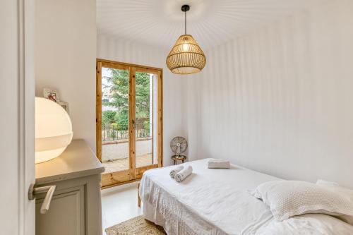 a white bedroom with a bed and a window at Villa la Barrufa in S'agaro