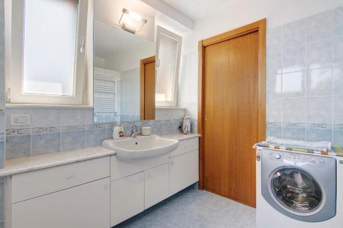 a bathroom with a sink and a washing machine at Residenza ai Noci in Lanzo dʼIntelvi