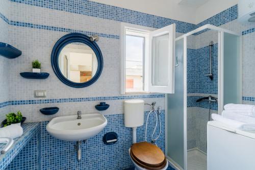 a blue tiled bathroom with a sink and a mirror at Casa Azzurra a Torre dell'Orso in Torre dell'Orso