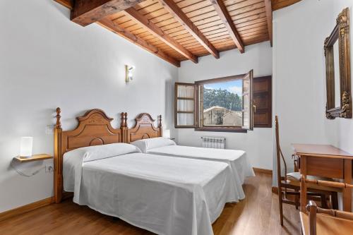a bedroom with a bed and a desk and a window at Apartamentos El Rincón de Bustio in Bustio