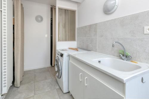 a white bathroom with a sink and a washing machine at Maison Ty Gwen in Le Pouliguen