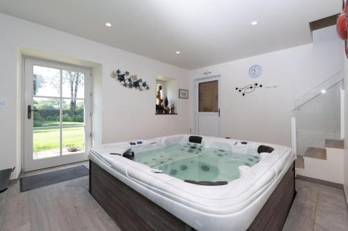 a large bath tub in a room with a window at Chambre - Spa - Piscine - Sauna in Brech