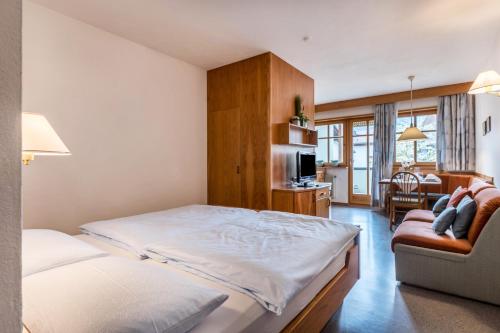 a bedroom with a bed and a couch and a tv at Taufner Apartement A 105 in Parcines
